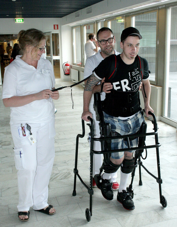 Patienten Dennis Biancofiore, som är helt förlamad från midjan och ner, tränar i Ekson. På bilden syns även sjukgymnasterna Margareta Arnell och Peter Svensson. Foto: Hannes Ljunghall.